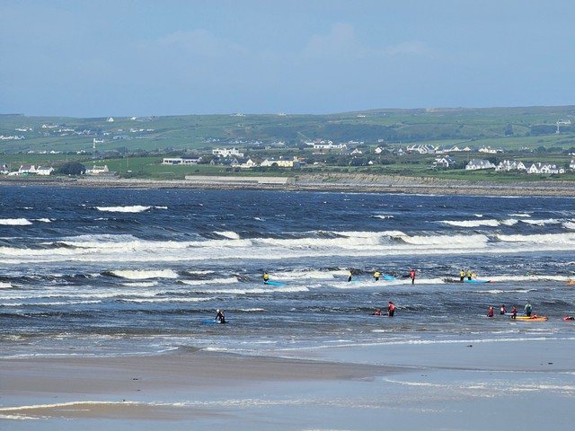 a few beginner surfers in the shallows with lots of whitewater at low tide